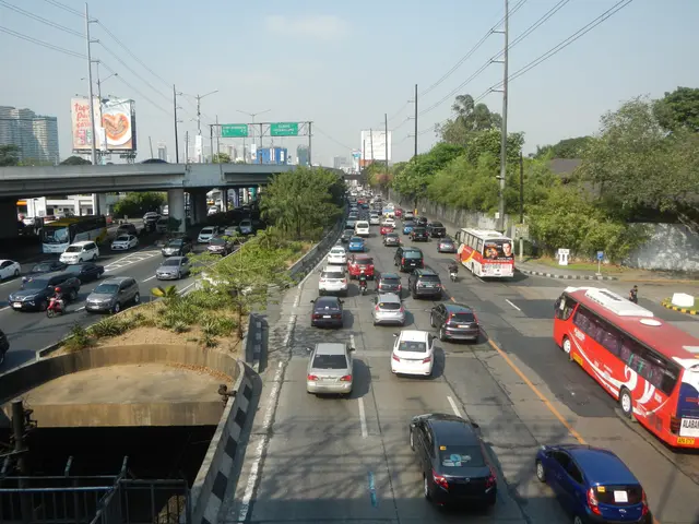 The image shows a busy street filled with lots of cars and buses, as well as electric poles with...