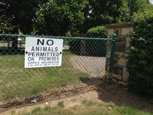 The image shows a sign on a chain link fence that reads "No Animals Permitted on Premises"...