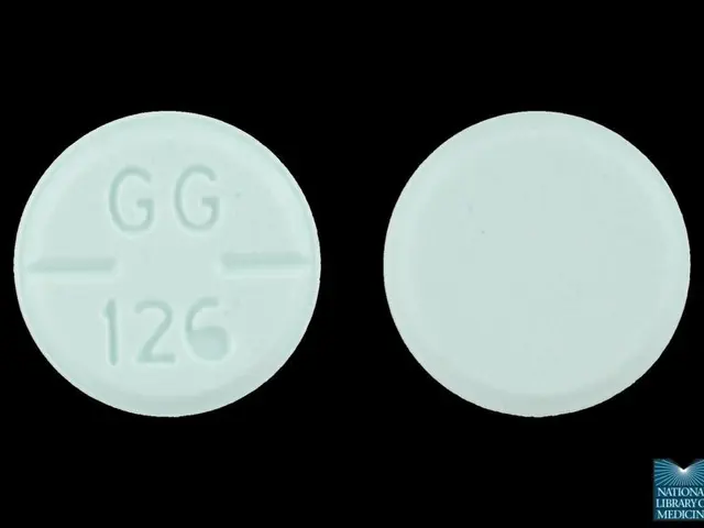 The image shows a white pill with the word "gg" on it against a black background, with a watermark...