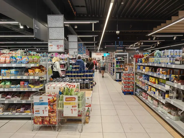 The image shows the inside of a supermarket with people shopping in it. There are racks filled with...