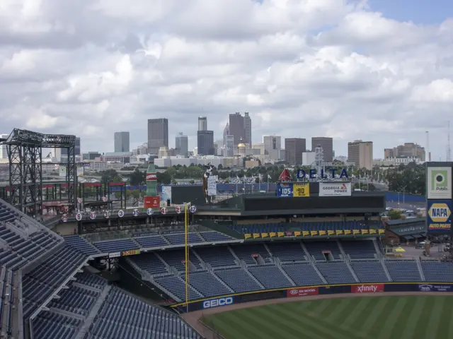 The image shows a baseball stadium with a view of the city skyline in the background. The stadium...