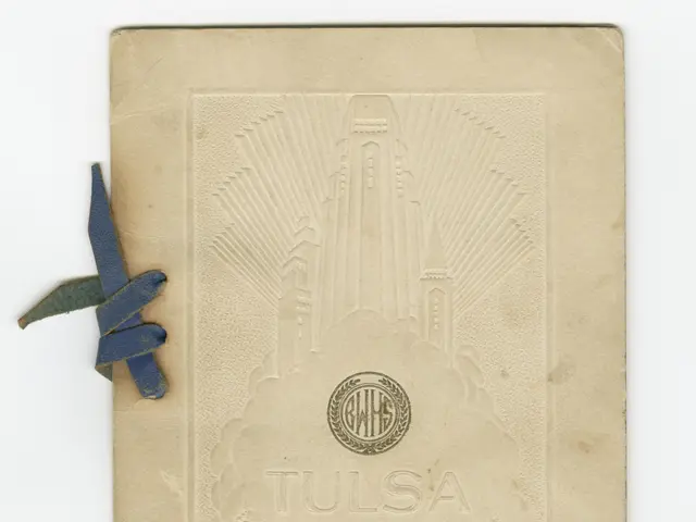 The image shows an old book with a blue ribbon tied around it, set against a white background. The...