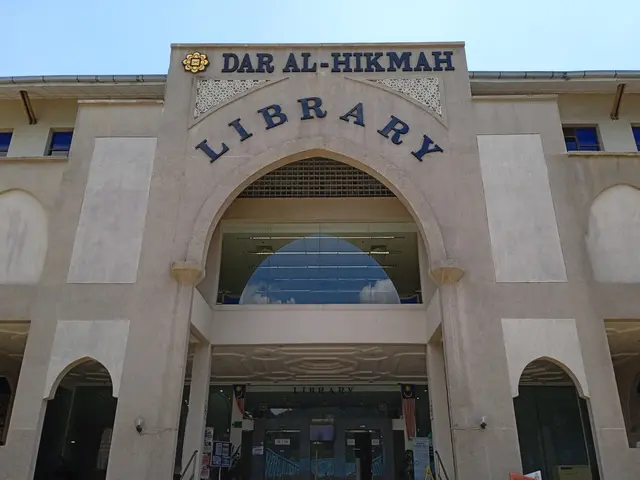 The image shows the Dar Al-Hikmah Library in Dubai, UAE. It is a large building with glass walls...