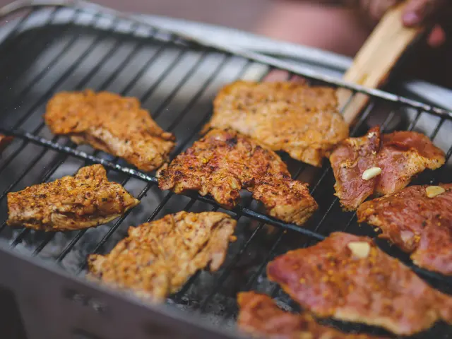 The image shows a person grilling meat on a barbecue grill with a pair of tongs. The background is...