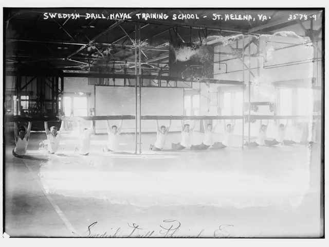 The image shows a black and white photo of a group of people doing gymnastics in a gym, with poles,...