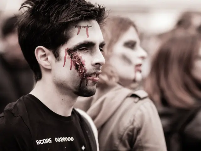 The image shows a group of people dressed up as zombies, with a man in the foreground wearing a...