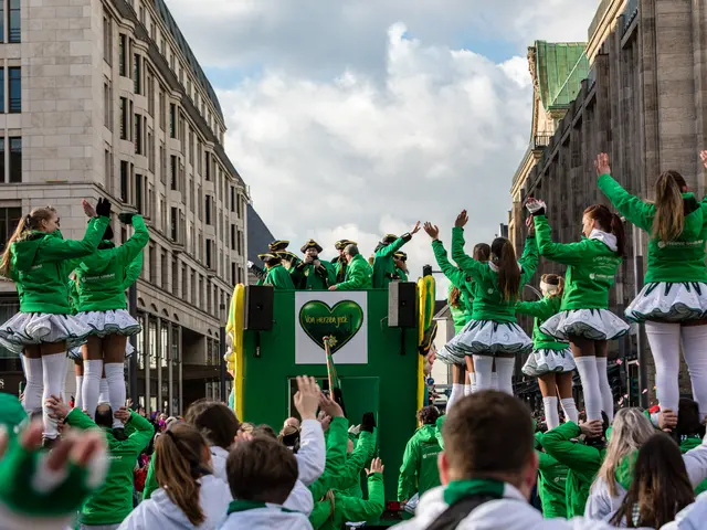 The image shows a group of people in green shirts and white skirts standing on top of a float in a...