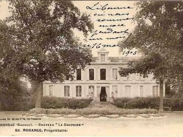 The image shows an old postcard of a large white building with windows, doors and pillars,...