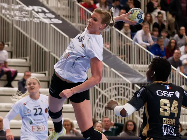 The image shows a group of women playing a game of handball on a court, with a ball in the air. In...