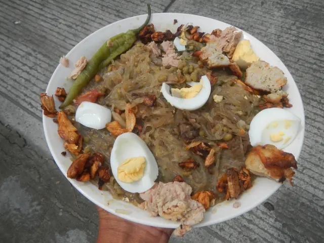 The image shows a person holding a plate of nasi lemak, a traditional Indonesian dish consisting of...