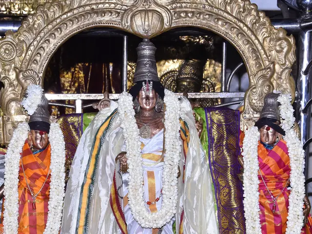 The image shows a statue of Lord Vishnu in a temple, adorned with garlands and surrounded by...