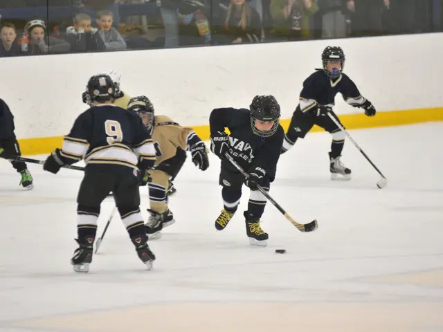 The image shows a group of young boys playing a game of ice hockey on an ice rink. They are wearing...