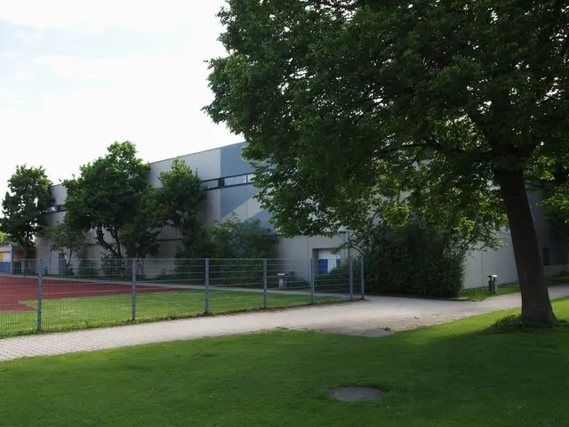 The image shows a large building with a tennis court in front of it, surrounded by a metal fence, a...