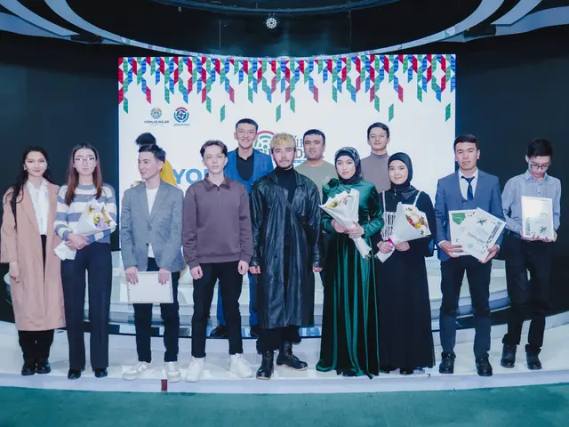 The image shows a group of people standing on top of a stage, each holding a bouquet of flowers and...