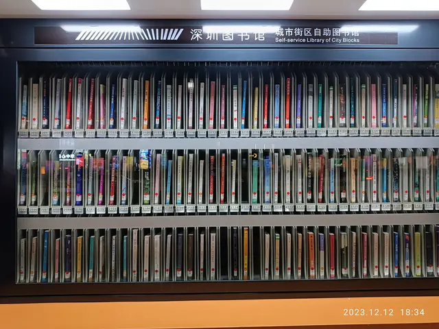 The image shows a library filled with lots of books on shelves, illuminated by lights at the top....