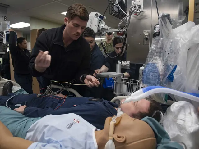 The image shows a man laying on top of a hospital bed next to a dummy, surrounded by a group of...