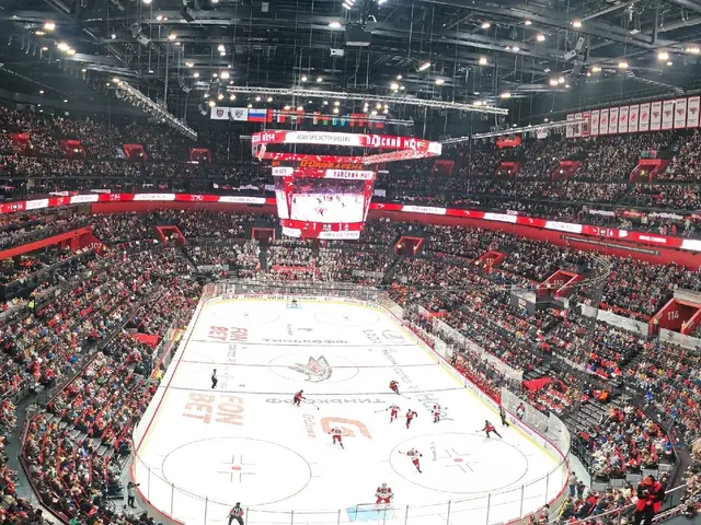The image shows a large arena filled with lots of people watching a hockey game. The arena is...
