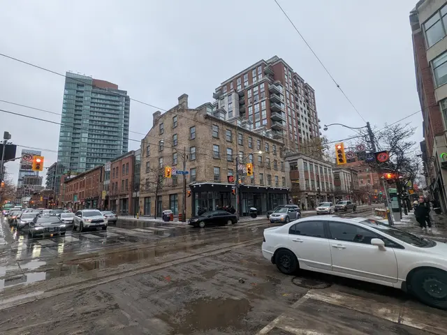 The image shows a city street filled with lots of traffic on a rainy day. We can see vehicles on...