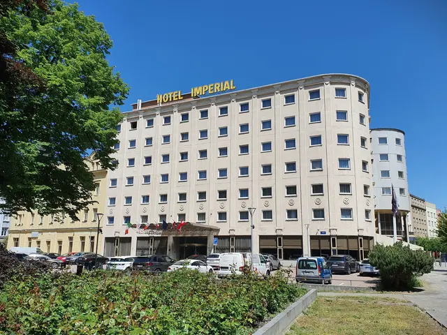 The image shows the Imperial Hotel in Berlin, Germany. It is a large building with windows,...