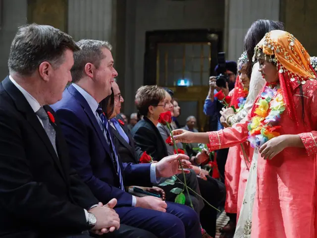 The image shows a group of people sitting next to each other in a room. In the center of the group...