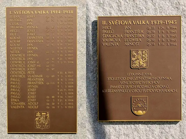 The image shows two plaques on the side of a stone wall, each with text and a logo. The plaques are...