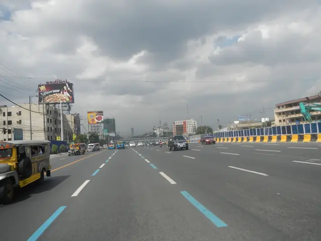 The image shows a city street filled with lots of traffic on a cloudy day. We can see vehicles on...