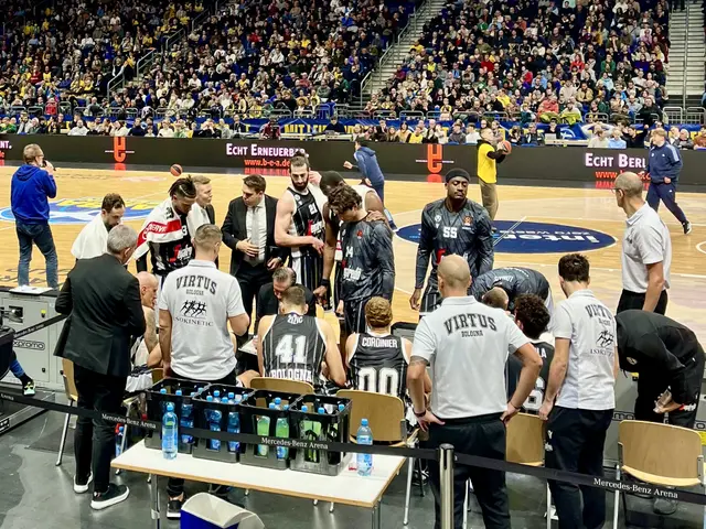 The image shows a group of men standing on top of a basketball court, surrounded by a crowd of...
