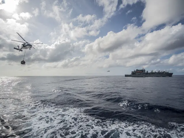 The image shows a helicopter flying over the ocean with a boat in the background. The sky is filled...
