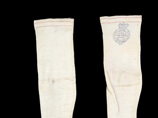 The image shows a pair of white socks with a red stripe on them against a black background. The...