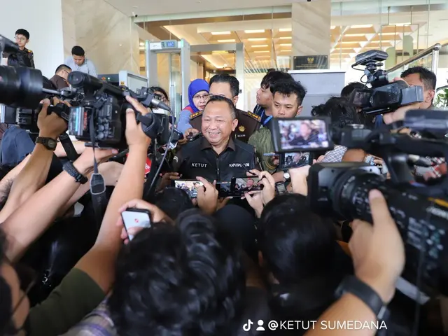 The image shows a group of people standing in front of a crowd of reporters, some of whom are...