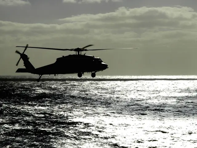 The image shows a helicopter flying over the ocean on a cloudy day, with the water below and the...