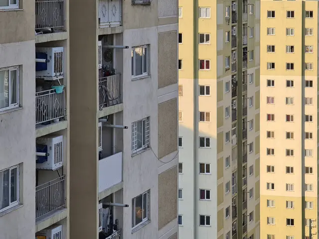 The image shows a tall apartment building with many windows and balconies, railings, and air...