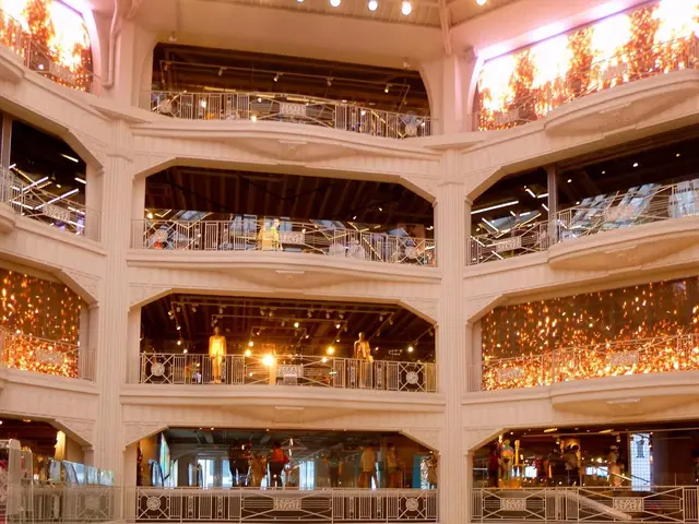 The image shows a large atrium filled with lots of people walking around, some of them carrying...