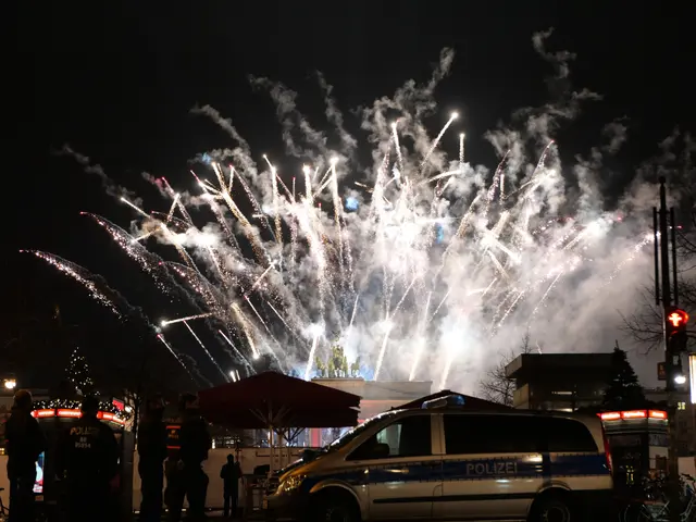 The image shows a police car parked in front of a crowd of people, illuminated by the lights of the...