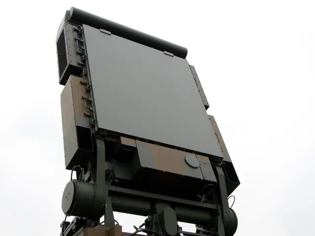 The image shows a military vehicle with a radar on top of it, set against a backdrop of a clear...