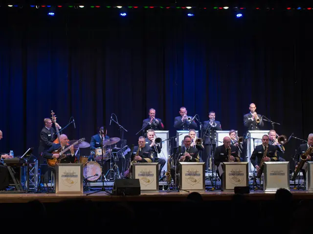 The image shows a group of people on a stage playing musical instruments, with mics and stands set...