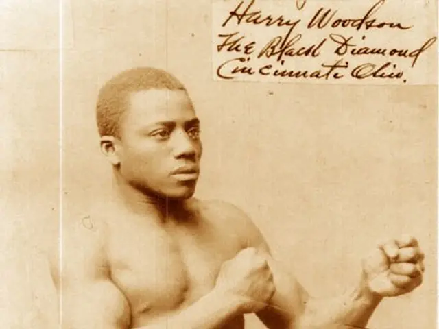 The image shows an old photo of a man in a boxing ring, with text written on it. He is wearing...