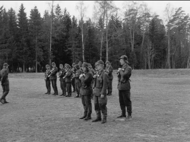 The image shows a group of men standing next to each other in a field, wearing caps and holding...