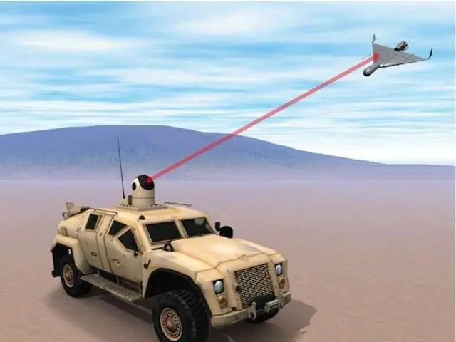 The image shows a military vehicle in the desert with a red laser beam coming out of it, and an...