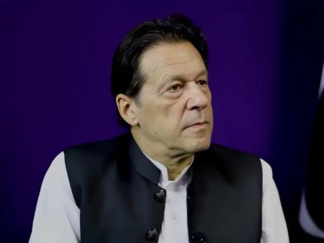 The image shows Imran Khan, the Prime Minister of Pakistan, wearing a black and white dress against...