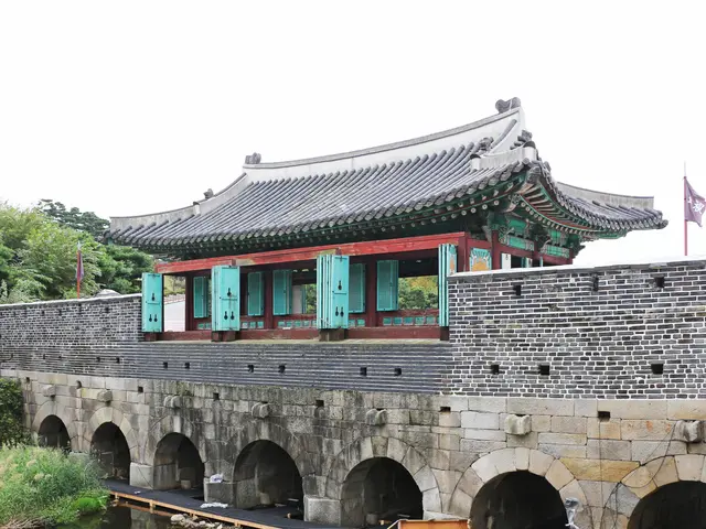 The image shows a gyeongbokgung palace in Seoul, South Korea, with a bridge over a body of water....