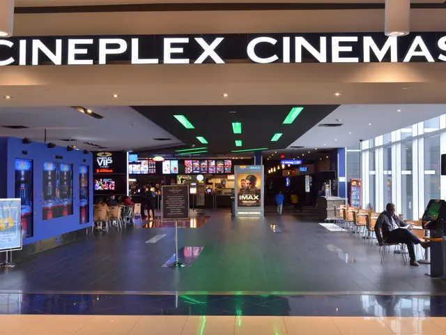 The image shows the inside of Cineplex Cinemas in London, England. There are people sitting on...