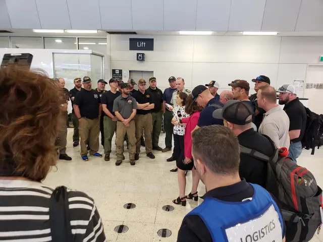 The image shows a group of people standing in line at an airport, wearing caps and bags. In the...