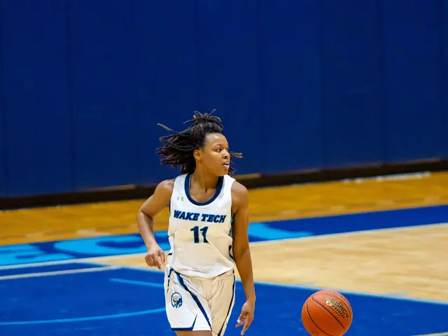 The image shows a woman in a blue and white uniform dribbling a basketball on a court. She is...
