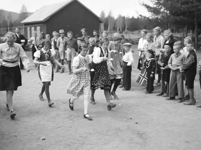 The image shows a group of children playing soccer in front of a crowd of people, some of whom are...