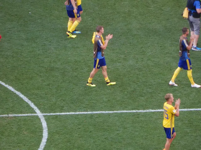 The image shows a group of men standing on top of a soccer field, clapping their hands in...