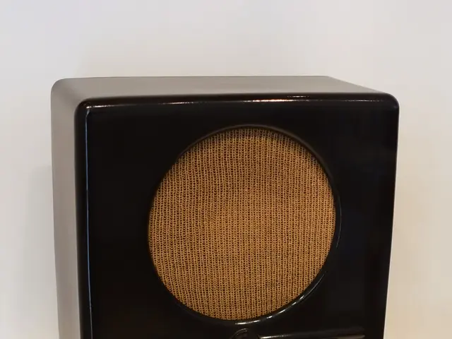 The image shows a black radio sitting atop a white pedestal, with a wall in the background.