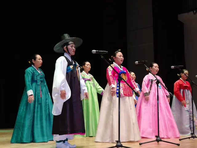 The image shows a group of people standing on top of a stage, wearing traditional Korean clothing...