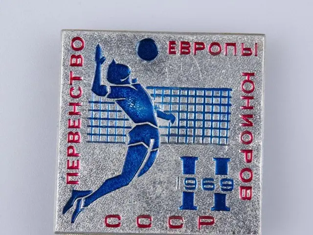 The image shows a silver medal with a picture of a man playing volleyball on it. The medal is...