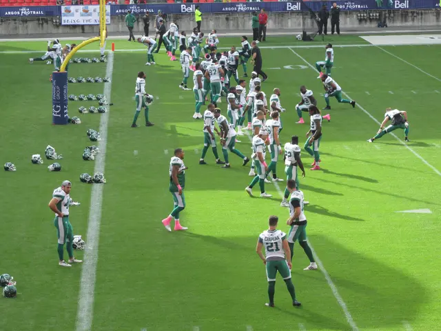 The image shows a group of people standing on top of a lush green field, with helmets scattered...